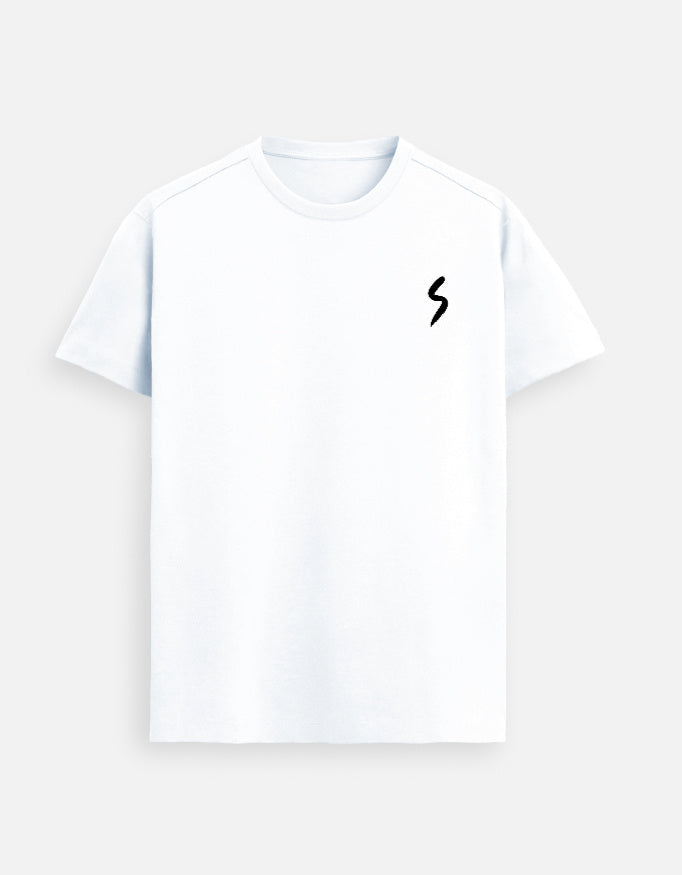 Woman wearing a White Lilak T-shirt featuring a small black minimalist ‘S’ symbol on the left chest, standing indoors in soft natural light with a calm expression