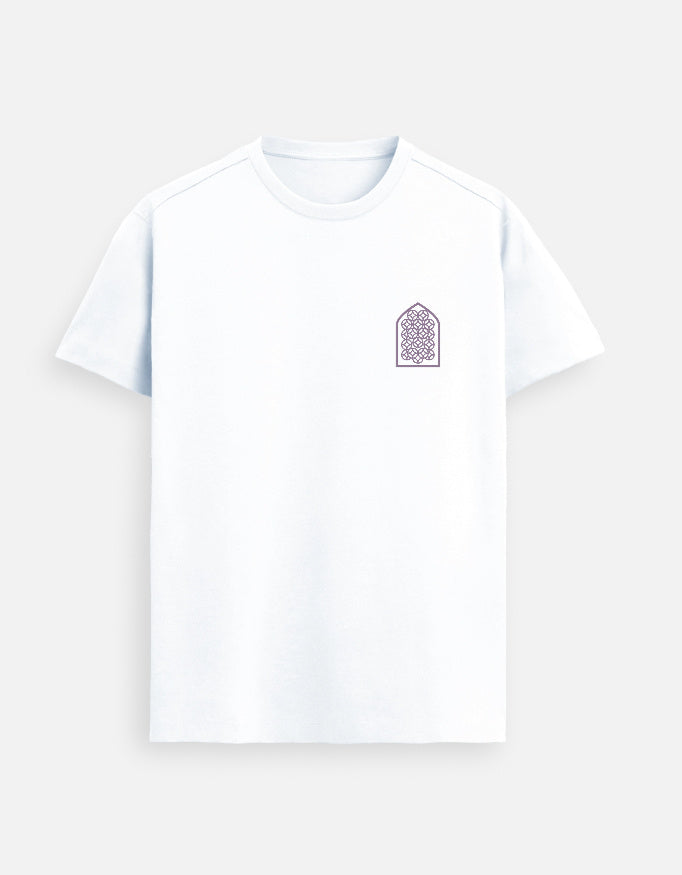 Indian male model wearing a White T-shirt with a purple geometric arch design on the chest, standing in a sunlit minimalist studio with soft shadows and a large window