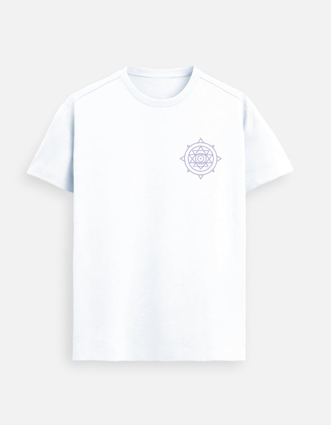 Male model wearing a White Lilak Supima cotton T-shirt featuring a minimal lavender mandala design on the chest, standing in a softly lit modern indoor setting with natural light and decor in the background