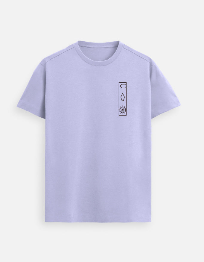 Woman walking down a sunlit city street wearing a Lavender Lilak T-shirt with a minimal vertical graphic on the left chest, paired with blue 