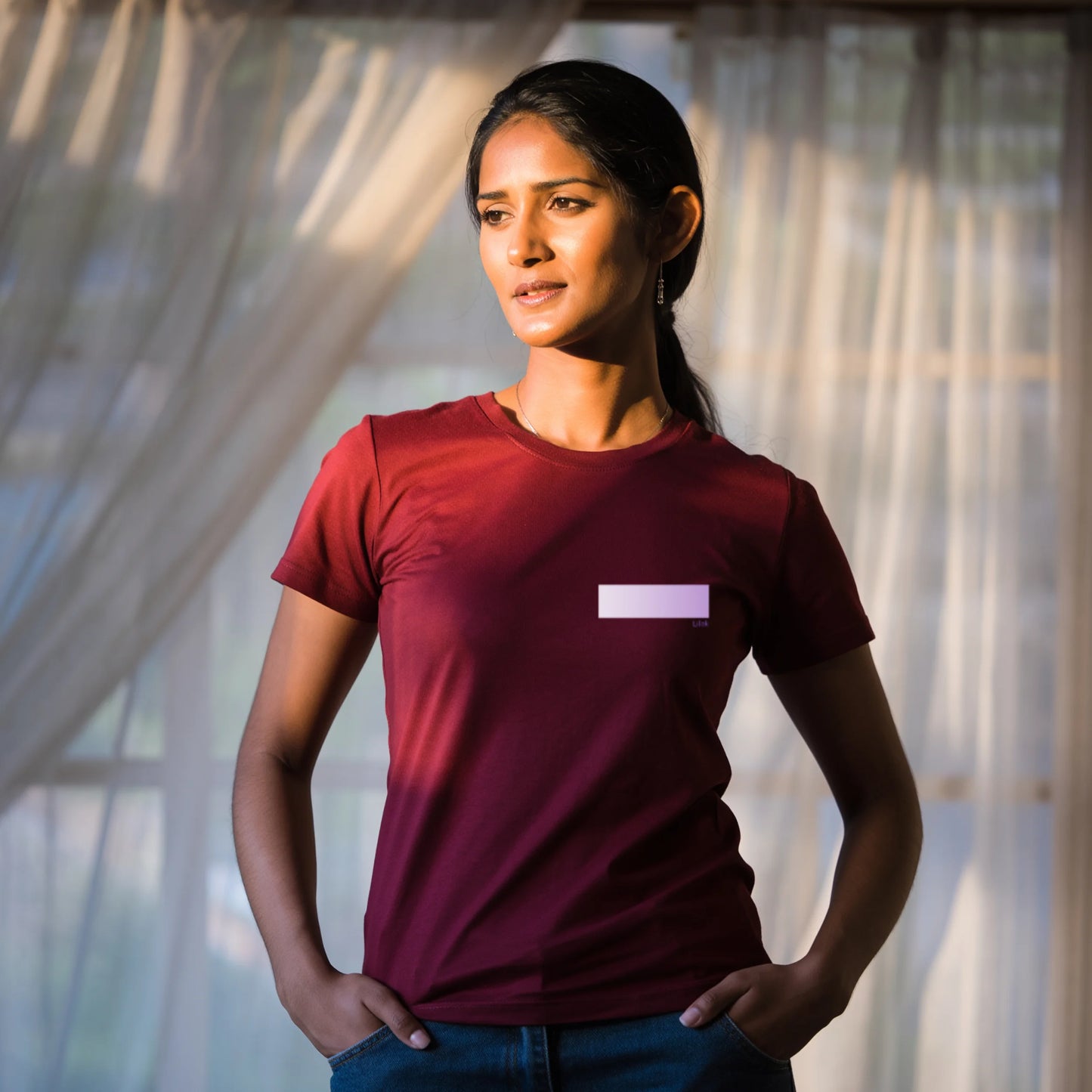 Woman wearing a red premium supima cotton t-shirt with a small white logo, standing against a blurred natural background.