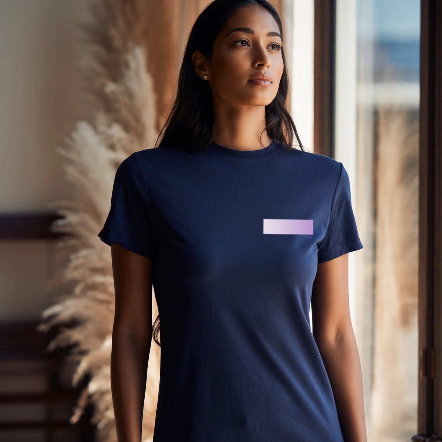 Woman wearing a navy blue premium supima cotton t-shirt with a small purple logo, standing indoors.